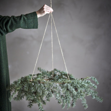 Cedar Artificial Christmas Wreath 70cm in green, held by a cord against a grey background, with frosted cedar sprays and small cones trailing from the ring.