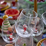 Clear glass stemless tumbler from the Misa Christmas set, featuring a candy cane figure on its base, displayed among festive table decor.