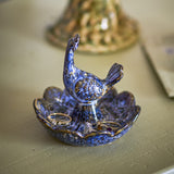 Kali Flower Stoneware Bowl 9.5cm in blue, a scalloped ceramic ring dish with a bird figure rising from its centre, holding rings, set on a light surface.