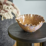 Nash Stoneware Bowl 24.5cm in brown with a ruffled, wavy rim and glossy ceramic finish, shown on a dark round side table beside a textured throw.