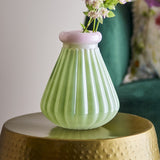 Judith Ribbed Glass Vase 24.5cm in green with a pink-rimmed neck, holding flowers on a gold side table beside a teal armchair.