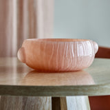 Lalie Ribbed Glass Bowl 20x12.5cm in pink, round with textured ribbed sides and two rounded side lugs, shown on a marble-topped table against a soft pink curtain backdrop.