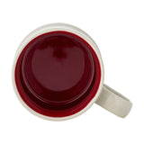 Top-down view of Kenai Embossed Stoneware Christmas Cup, cream exterior with a deep red glazed interior and matching rim, handle visible, set against a plain white background.