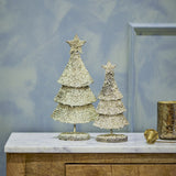 Radha Star Iron Christmas Decorations in gold, two glittery tiered trees with star toppers on round bases, displayed on a marble-top sideboard.