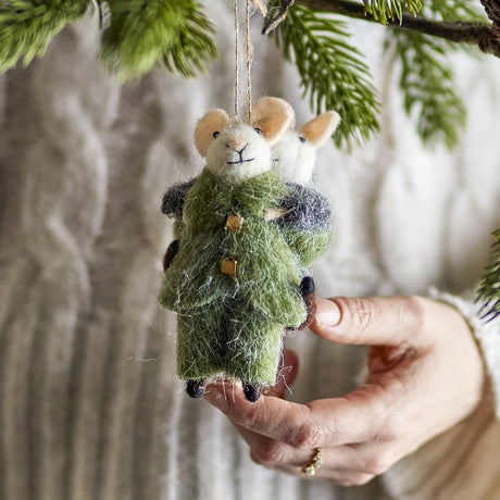 Peo Wool Christmas Tree Decoration in green, felted mice piggyback design with button details, hung from a pine branch and held by hand.