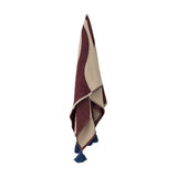 Cimmi Christmas Throw in burgundy and beige woven fabric with a sweeping curved pattern, shown hanging with navy corner tassels against a plain white background.