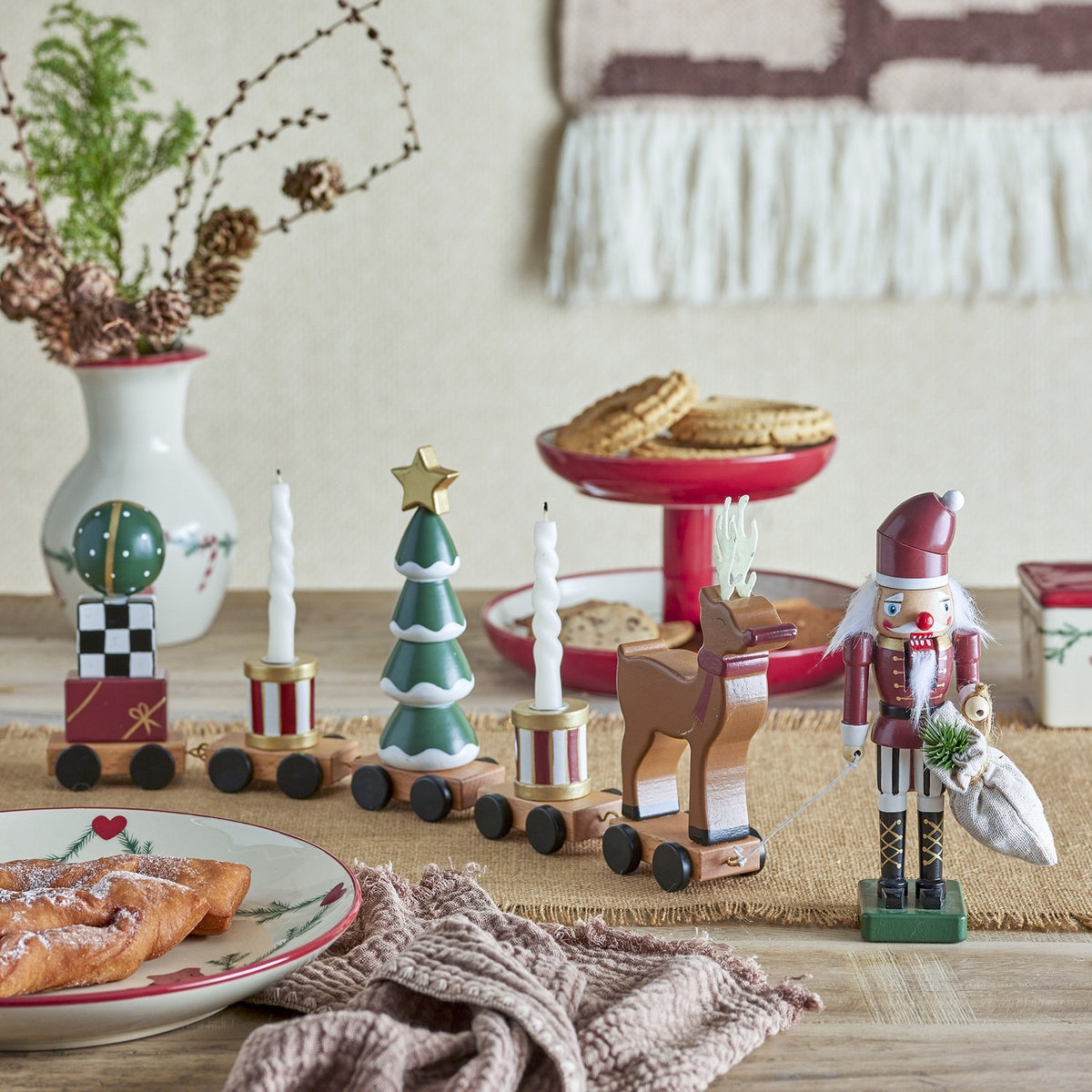 Vadim Christmas Decoration wooden train with bauble, gift wagon, candle drums, snow-tipped tree and reindeer, styled on a table beside a nutcracker figure and festive décor.
