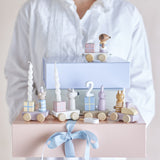 Junaid Cat Birthday Decoration wooden train with number "2" candle holder, animal figures and gift-box wagons, held atop pink and blue boxes with a blue ribbon.
