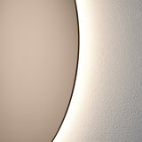 Close-up of the bronze glass edge with the warm light spilling onto the wall behind, showing how far the glass stands off it.