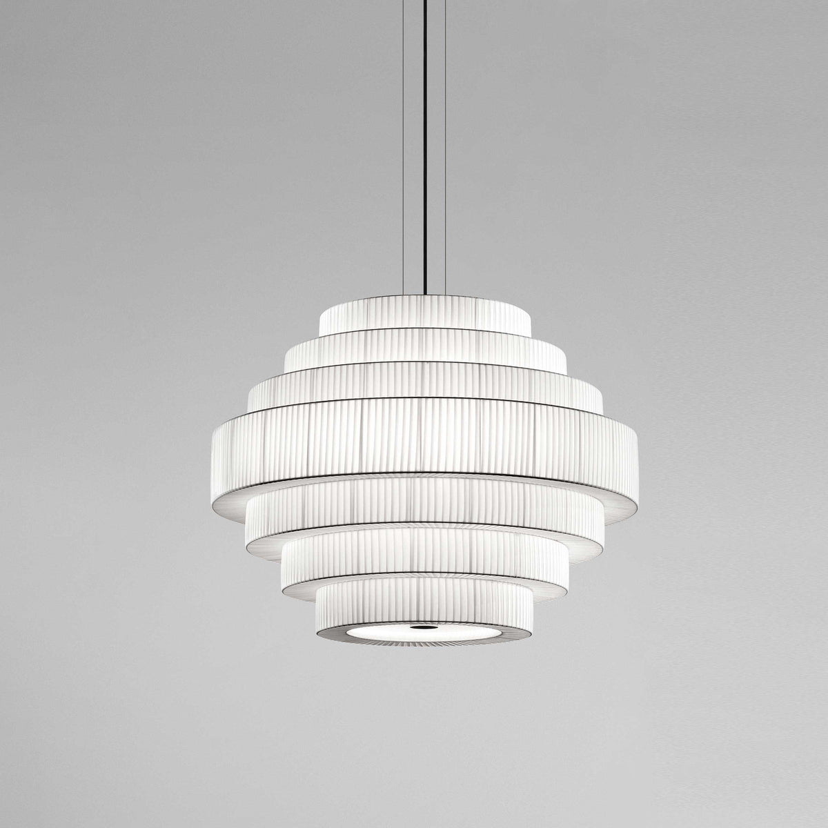 Mos 03 Ribbon Tiered Pendant Light with stacked rings of pleated white translucent ribbon forming a rounded tower shape, suspended on a slim cord against a plain grey background.