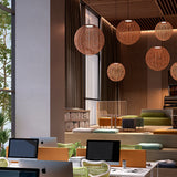 Nans Sphere S/80 woven outdoor pendant lights in red with open-weave spherical shades, shown in clusters above a lounge and workspace seating area.