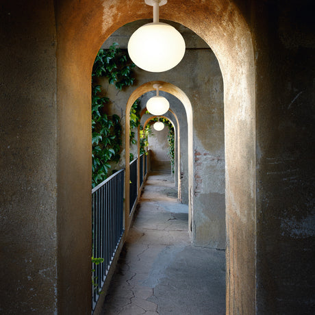 Elipse PF/30 Globe LED outdoor ceiling light with white spherical shade on a short stem and round canopy, shown installed in a vaulted stone archway corridor.