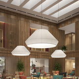 Mei 150 Ribbon Pendant Light in white translucent ribbon with a wide tapered shade, shown in three sizes above a wood-panelled lounge with seating.