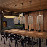 Nans S/31.2 woven LED outdoor pendant lights in beige, four cylindrical lantern shades hung at staggered heights above a wooden dining table on a covered patio.