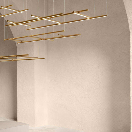Hilow White Diffuser Frame LED pendant light in brass finish, crossed linear bars suspended from a vaulted ceiling in a plastered room setting.