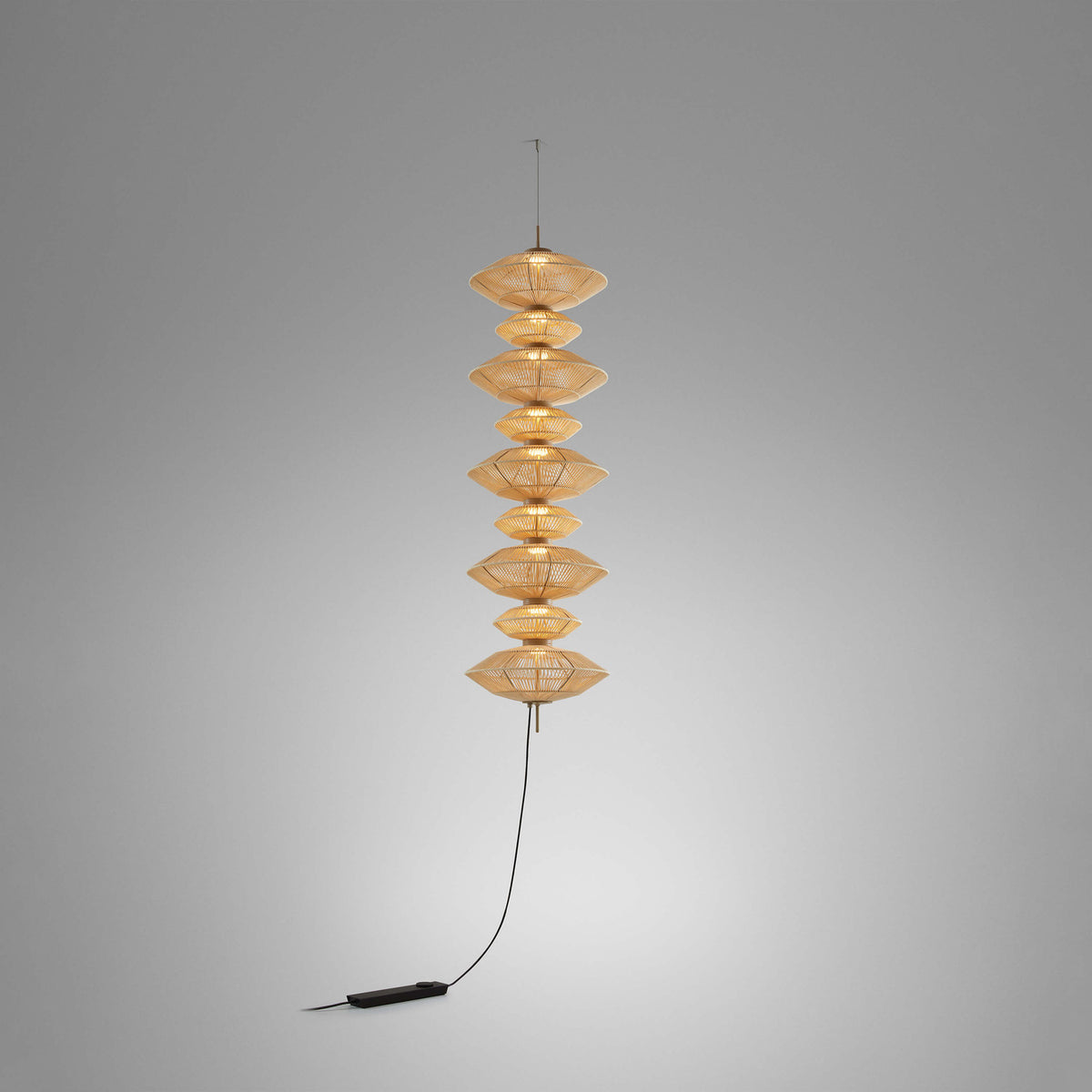 Yuyun S/9C/I fabric LED pendant light with nine stacked beige woven cotton tiers forming a tall column, hung from a slim cable against a plain grey background.