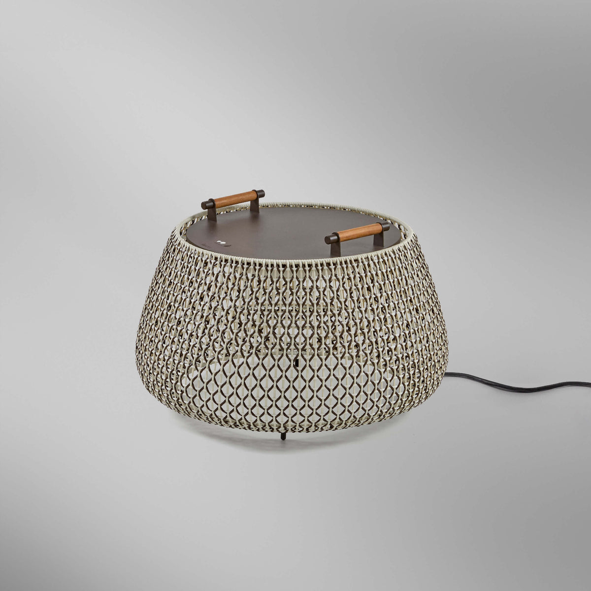 Nans Bag/38 Wood LED outdoor floor lamp with a round, drum-shaped brown woven cord shade, flat dark top, and two teak wood handles, shown on a plain light grey background.