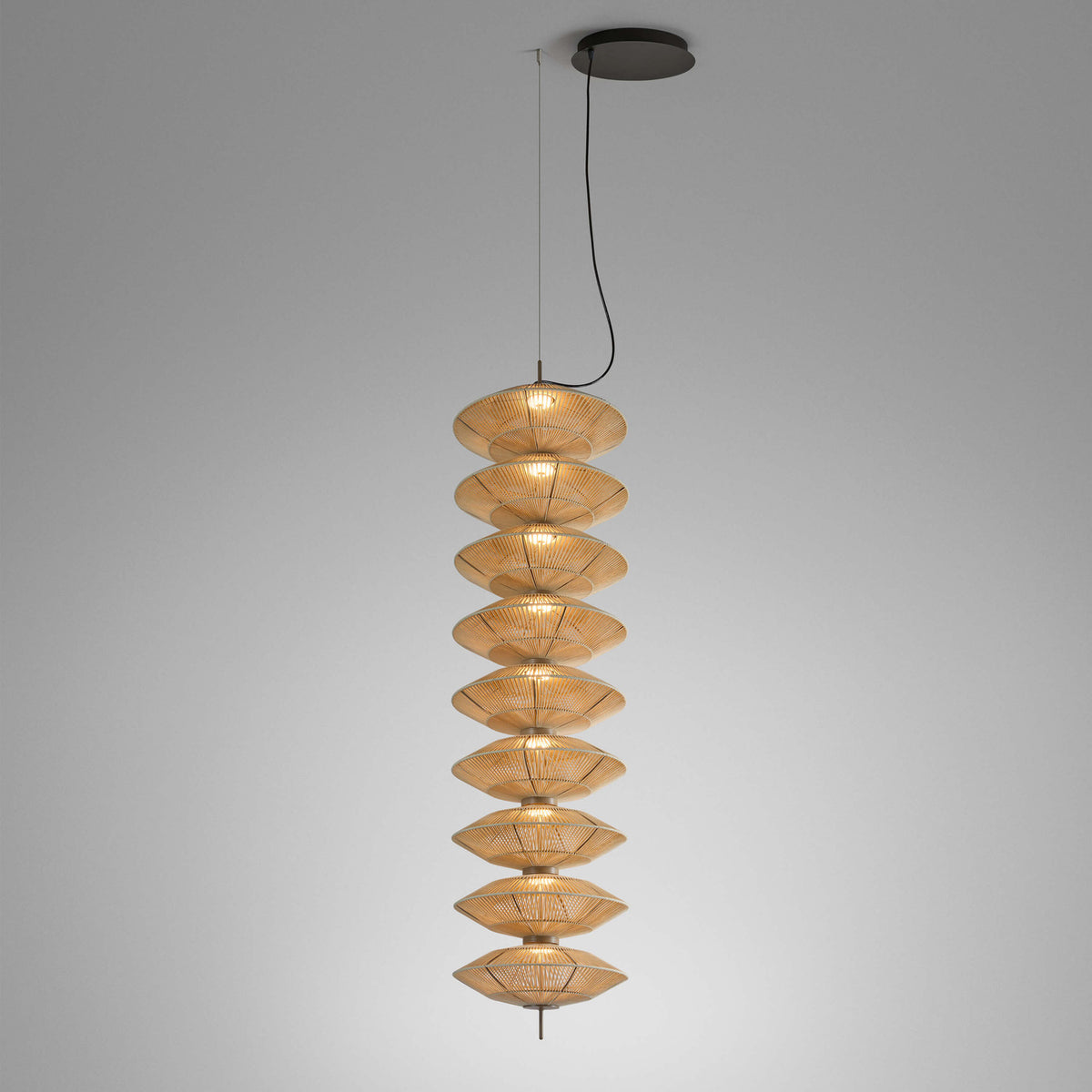 Yuyun S/9L pendant light with nine stacked woven cotton shades in satin beige, integrated LED, suspended from a black ceiling canopy on a plain grey background.