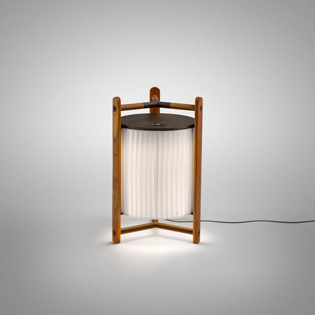 Kando M/40 lantern-style LED table lamp with pleated white translucent ribbon shade in a brown wooden three-legged frame, dark top disc, on a plain light grey background.