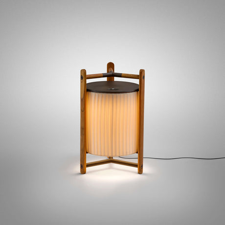 Kando M/40 Ribbon LED table lamp with cream pleated fabric shade and teak wood tripod frame, lit against a plain light grey background.
