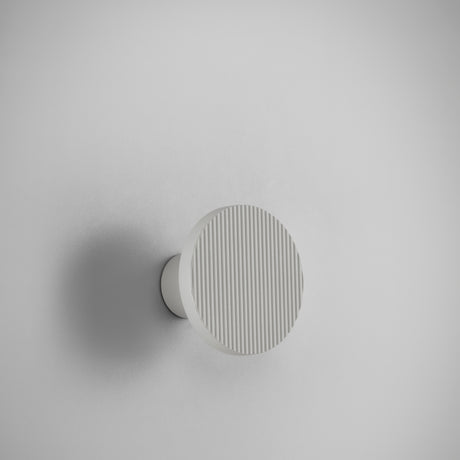 Arid A/01 Aluminium LED wall light in Textured White, round fluted disc on a short stem, shown against a plain light grey background.
