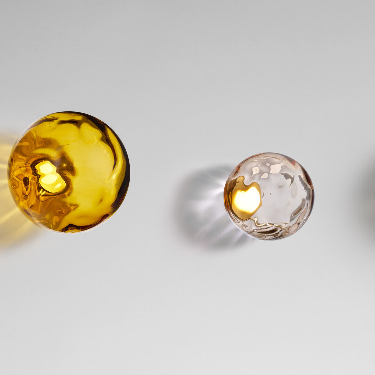 Murané Glass Sphere Wall & Ceiling Light, 15cm amber glass globe with rippled texture and integrated LED glow, Brushed Champagne mount, on a plain light grey background.