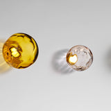 Murané Glass Sphere Wall & Ceiling Light, 15cm amber glass globe with rippled texture and integrated LED glow, Brushed Champagne mount, on a plain light grey background.