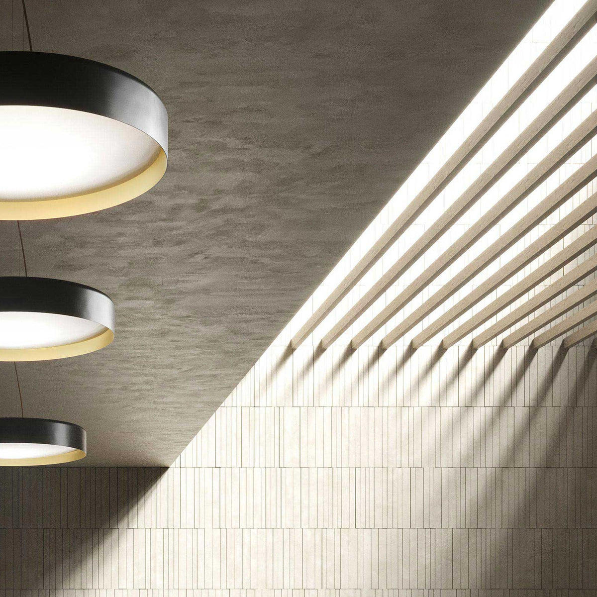 Ginevra 80cm LED pendant lights in matt black with brass inner rim, shown tiered in a ceiling installation above a sunlit ribbed wall.