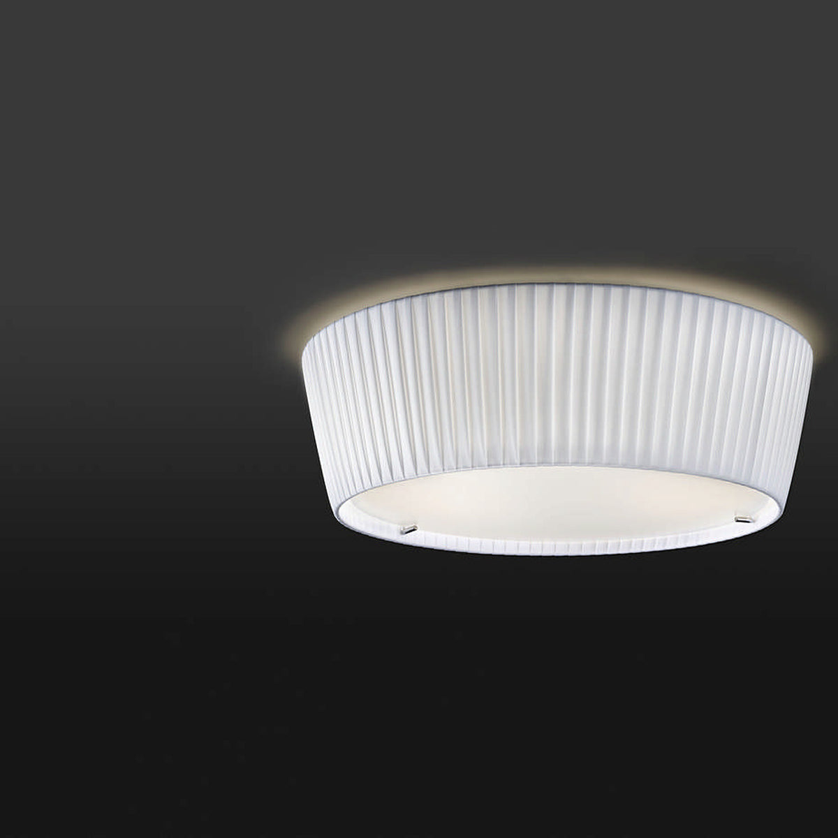 Plafonet 43 Ribbon Drum ceiling light with a pleated white translucent fabric shade and illuminated top edge, shown against a dark background.