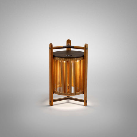 Kando M/40/R rechargeable outdoor table lamp with sand nautical cord cylinder wrapped in a teak wood frame and dark metal top and arms, shown lit on a plain grey background.