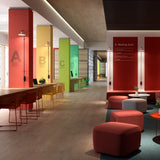 Platet A/06 wall lights with built-in switch mounted on coloured pillars in a modern lounge, slim aluminium rods curving to single conical shades.
