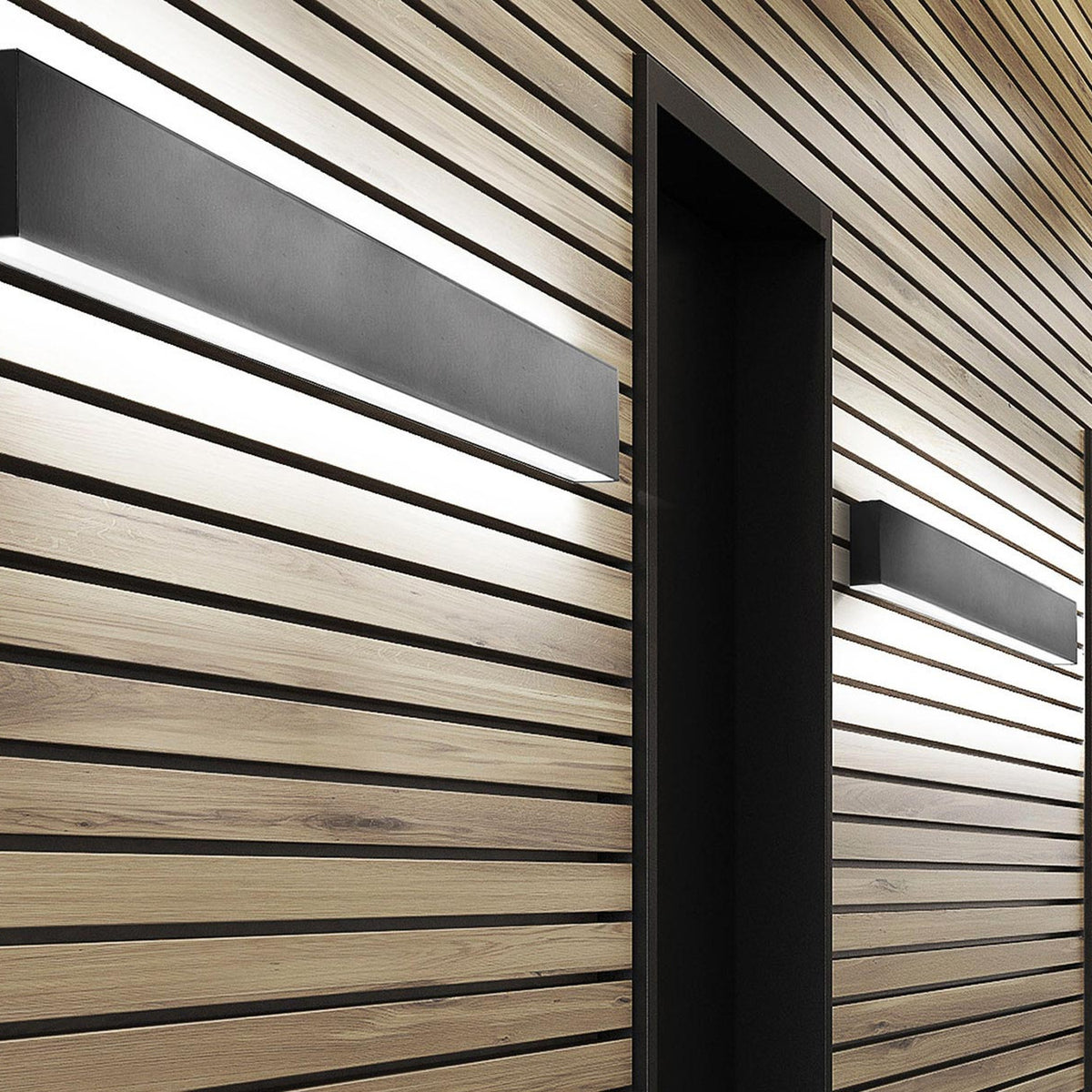 Giano Aluminium Linear LED Wall Light in black, a slim rectangular bar mounted on a horizontal wood-slatted wall, casting warm white light upward and downward near a dark recessed doorway.
