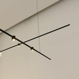 SIS Spot 36° cylinder LED track spotlights in black, mounted on slim ceiling tracks with warm white downlight, set against a plain light grey ceiling.