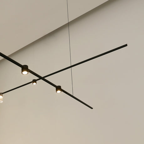 SIS Spot 36° cylinder LED track spotlights in black, mounted on slim ceiling tracks with warm white downlight, set against a plain light grey ceiling.