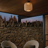 Nans PF/31 woven outdoor ceiling light with barrel-shaped beige fabric shade and dark mount, installed on a wooden patio ceiling above a stone wall.