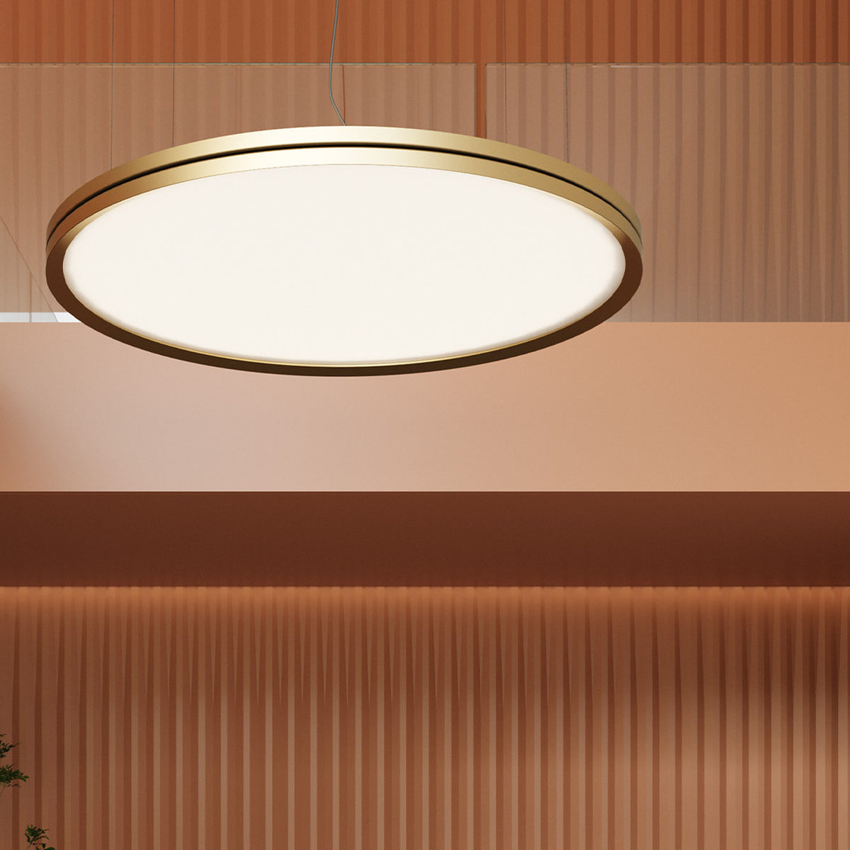 Lite Hole S90 round LED pendant light with a slim gold aluminium frame and flat white glowing disc, hung from thin cables above a dining area with warm panelled walls.