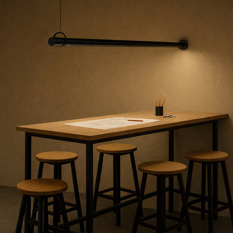 Solid WS 100 Tube LED Wall Light in matte black, a slim horizontal tube fixture mounted above a wooden desk, casting warm downward light with a fine cable support at one end.