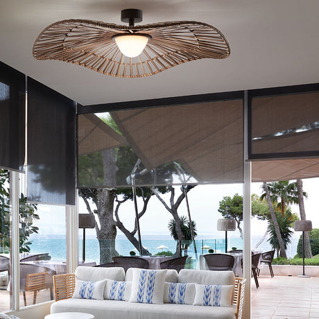 Mediterrània PF/105 Disc LED outdoor ceiling light with wide, wavy woven brown synthetic fibre shade and white rounded diffuser, shown above a coastal terrace seating area.