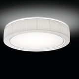 Urban PF/90 Ribbon LED ceiling light with a round drum shade in pleated white translucent fabric over an iron frame, broad white diffuser with silver trim, shown glowing against a dark background.