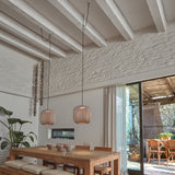 Nans S/31 woven LED pendant lights in brown with rounded barrel shades, hung at two heights above a wooden dining table in a rustic, beamed-ceiling room.