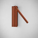 Arid A/03 LED wall light in textured terracotta aluminium, with a fluted upright plate and a slim angled tube, shown on a plain light grey background.