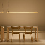 Solid SH Sens 220 cylinder LED pendant light in matte black, a slim 220cm tube suspended from two cables above a wooden dining table and chairs.