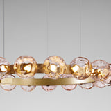 Murané R 25 ring chandelier with pink rippled glass spheres on a brushed champagne band, integrated warm white LED, shown against a plain grey background.