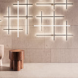 Hilow Black Diffuser Frame LED wall lights in Brushed Bronze, multiple criss-crossing linear fixtures installed on a textured panelled wall above a wooden stool.