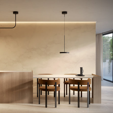 Dip Disc LED Pendant Light in matt black with a slim 25cm disc shade, shown above a dining table with tan chairs and a marble-effect wall.