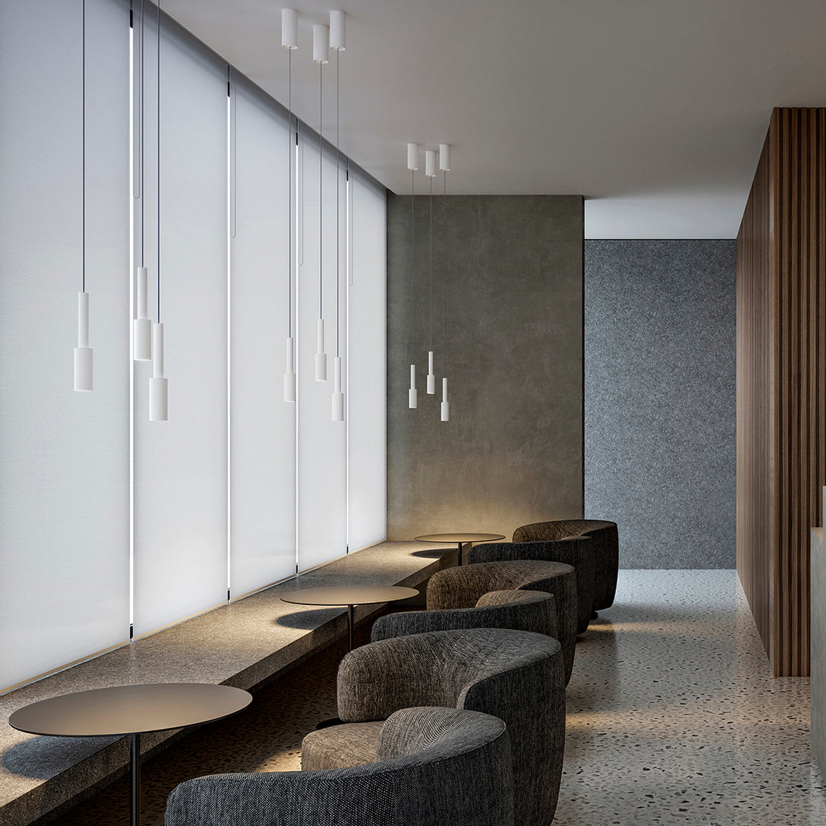 Tubino Aluminium LED Pendant Light in white, slim cylindrical heads on fine cables at varied drop heights, shown grouped above a seating area with grey armchairs and round tables.