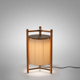 Kando P/76 Ribbon LED floor lamp with a cream pleated cylinder shade in a teak wood tripod frame and round brown top, lit against a plain grey background.