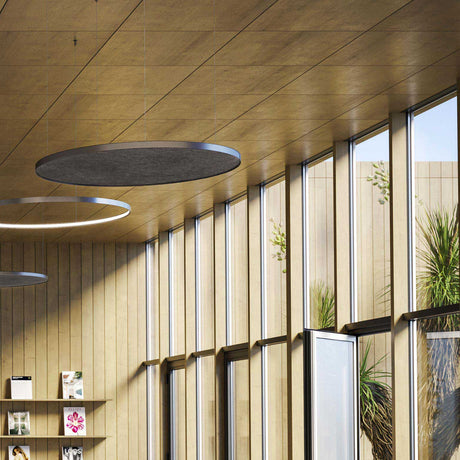 Zero Round Acoustic Panel 98cm in Brushed Titanium, a slim floating disc with grey flecked underside, suspended above ceiling-mounted ring pendant lights in a wood-panelled interior.