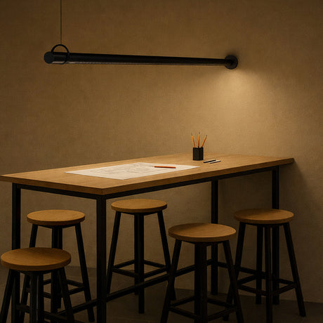 Solid WS 220 Tube LED wall light in matte black, a slim horizontal bar suspended by a cable loop above a wooden dining table, casting warm ambient light in a dining setting.