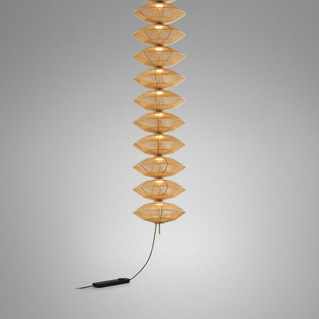 Yuyun S/11L/I pendant light with eleven stacked satin beige thread shades on a slim stem, illuminated, with black cord and foot dimmer, on a plain grey background.